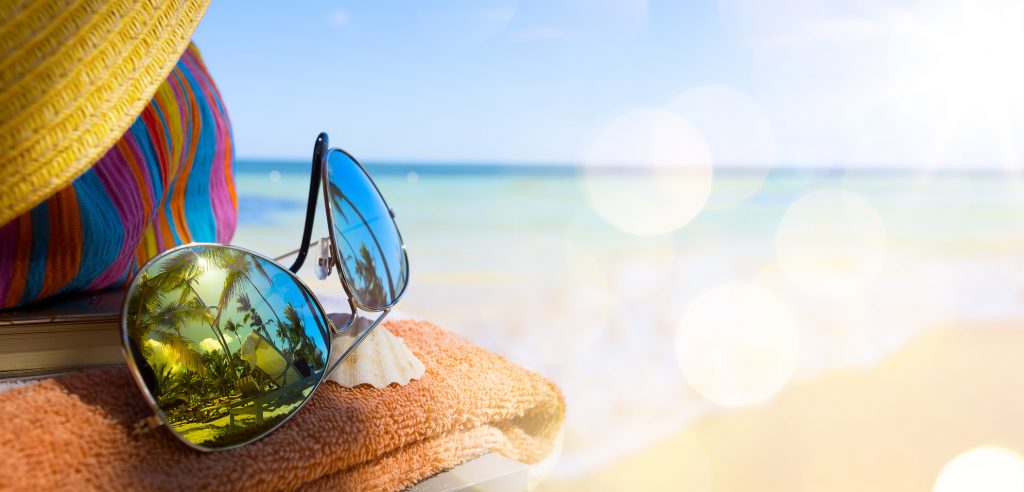 Straw hat, bag and sun glasses on a tropical beach