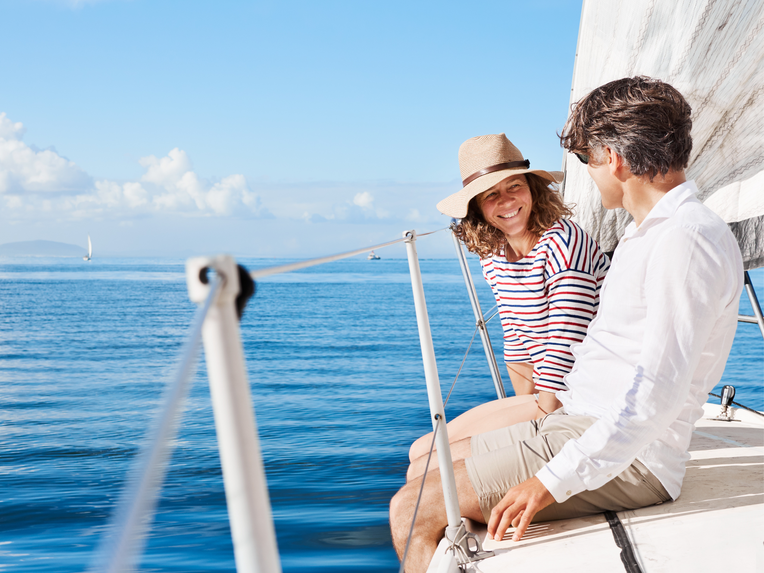 Mature lady and gentleman talking to each other on a sailing boat out at sea.